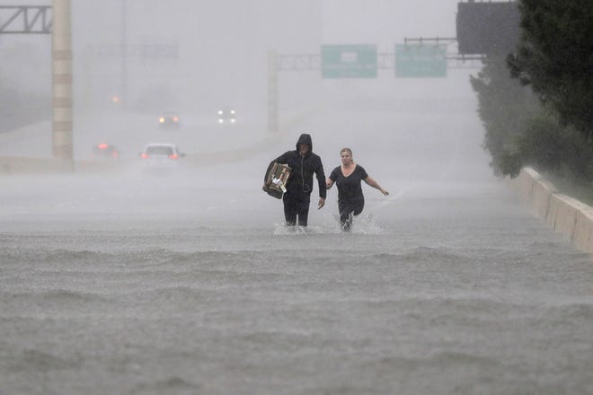 Two people walk down a flooded section of Interstate 610 in floodwaters from Tropical Storm Harvey on Sunday, Aug. 27, 2017, in Houston, Texas. (Associated Press)
