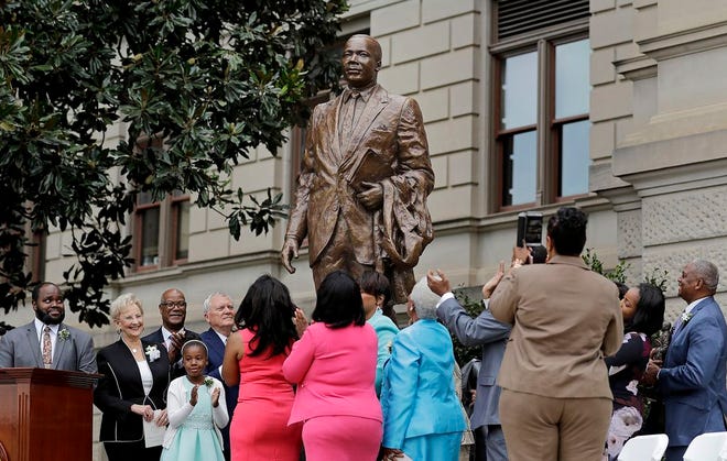 A statue paying tribute to civil rights leader Martin Luther King Jr. is unveiled by Georgia Gov. Nathan Deal, center left, members of the King family and others on the state Capitol grounds in Atlanta on Monday. The statue's unveiling Monday came more than three years after Georgia lawmakers endorsed the project. A replica of the nation's Liberty Bell tolled three times before the 8-foot bronze statue was unveiled on the 54th anniversary of King's "I have a dream" speech at the march on Washington.