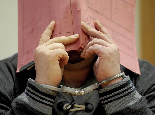 FILE - In this Dec. 9, 2014 file photo former nurse Niels Hoegel accused of multiple murder and attempted murder of patients, stands in the court room wearing handcuffs and covering his face with a file at the district court in Oldenburg, Germany. Niels Hoegel., accused of multiple murder and attempted murder of patients, covering his face with a file at the district court in Oldenburg, Germany. German authorities say Monday Aug. 28, 2017 they now believe that a nurse who was convicted of killing patients with overdoses of heart medication killed at least 84 people. Niels Hoegel was convicted in 2015 of two murders and two attempted murders at a clinic in the northwestern town of Delmenhorst. Oldenburg police chief Johann Kuehme said Monday authorities have now unearthed evidence of 84 killings. (Ingo Wagner/dpa via AP)