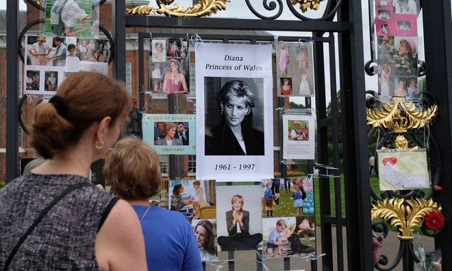 Tourists look at tributes and memorabilia for the late Diana, Princess of Wales outside Kensington Palace in London, Tuesday, Aug. 29, 2017. The tributes are placed on one of the ornamental gates at the palace ahead of the 20th anniversary of Princess Diana’s death, in a car crash in Paris Aug. 31, 1997. (AP Photo/Alastair Grant)