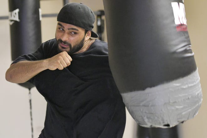 Aaron Ramprashad punches a bag at Primo's Boxing Gym in Leesburg on Aug. 16. Ramprashad opened the gym three months ago as a way to help the youth of Leesburg along with teaching boxing and fitness to anyone who is interested. [PAUL RYAN / CORRESPONDENT]
