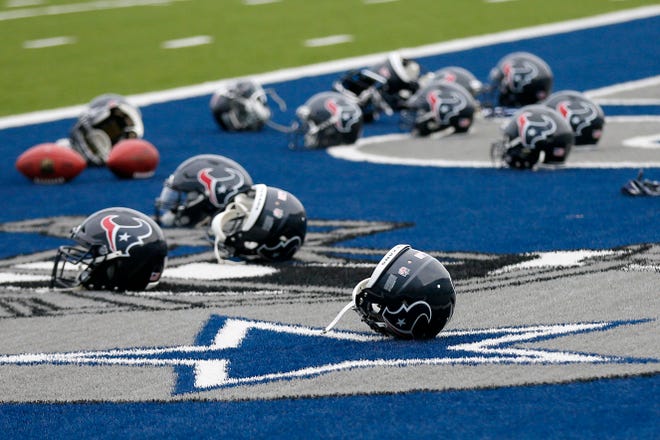 Several Houston Texans helmets sit over the Dallas Cowboys logo in the end zone as the Texans prepare for a morning work out at the Cowboys training facility Monday in Frisco, Texas.