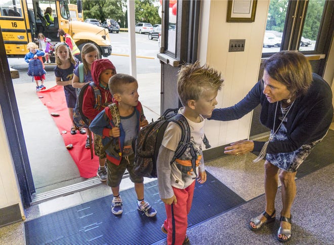Hathaway Elementary School Student Support Specialist Ann Grimes greets kindergartner Zachary Tilman on Wednesday during the first day of school in Portsmouth.