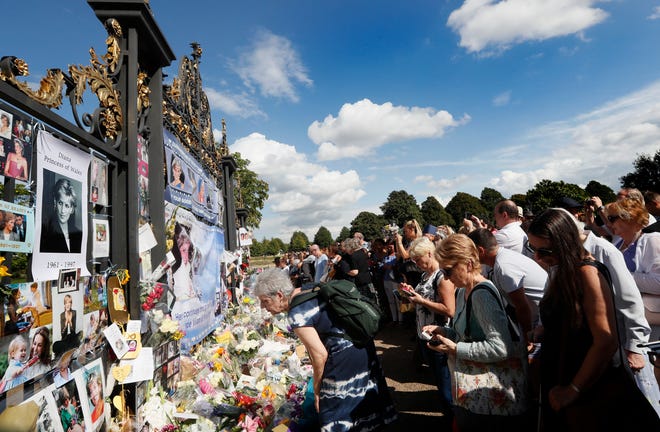 People crowd around the gates of Kensington Palace in London to pay tribute to the late Diana, Princess of Wales, Thursday, Aug. 31, 2017. Tributes at the gates are to mark the 20th anniversary of Diana's death, in a car crash in Paris on Aug. 31, 1997. (AP Photo/Kirsty Wigglesworth)