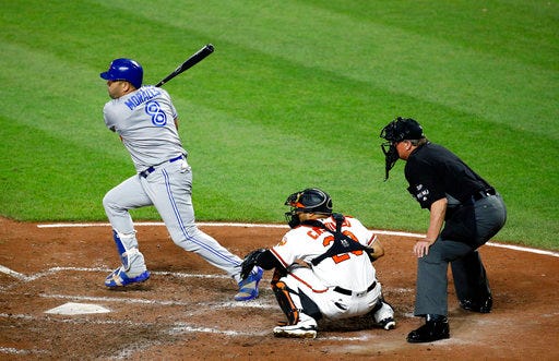 Toronto Blue Jays' Kendrys Morales, left, singles in front of Baltimore Orioles catcher Welington Castillo and home plate umpire Gerry Davis in the fifth inning of a baseball game in Baltimore, Thursday, Aug. 31, 2017. Ryan Goins scored on the play. (AP Photo/Patrick Semansky)