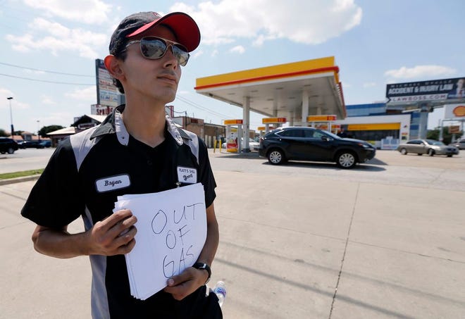 Employee Bryan Herrera holds a makeshift sign that reads, "Out of Gas," as he stands outside the Shell filling station where he works, in north Dallas, Thursday, Aug. 31, 2017. It's getting harder to fill gas tanks in parts of Texas where some stations are out of fuel and pump costs are spiking. A major gasoline pipeline shuttered due to Harvey may be able to resume shipping fuel from the Houston area by Sunday, which could ease gasoline shortages across the southern U.S. [AP Photo/Tony Gutierrez]