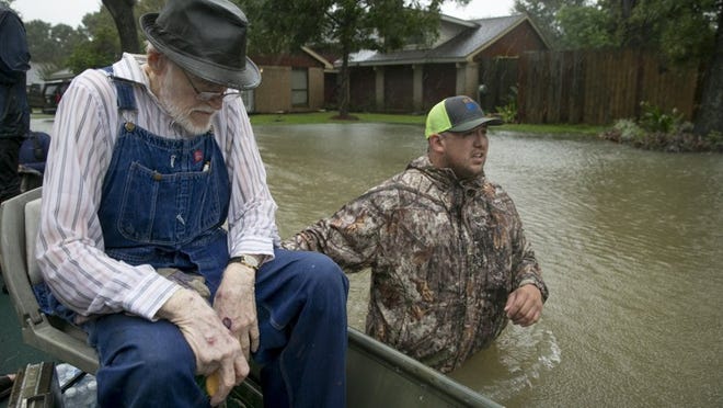 Thomas Luna, right, rescues Bobby Nelson, 78, from his flooded home in the Ravensway neighborhood of northwest Houston on Monday.