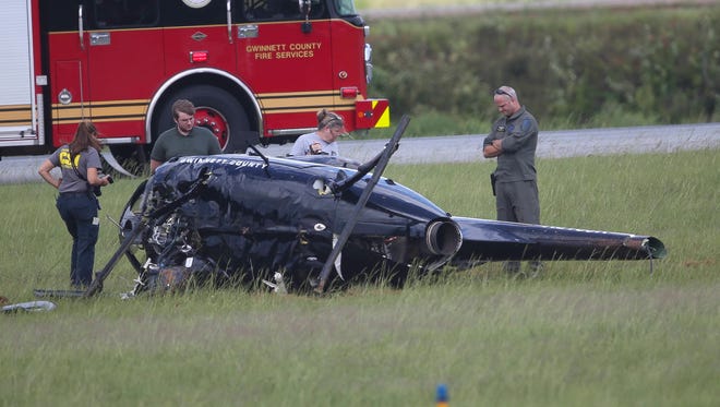 Investigators look over the wreckage of a Gwinnett County Police helicopter that crashed at the Gwinnett County Airport in Lawrenceville, Ga., on Friday, Sept. 1, 2017. The two officers onboard were taken to a local hospital for treatment. (AP Photo/John Bazemore)