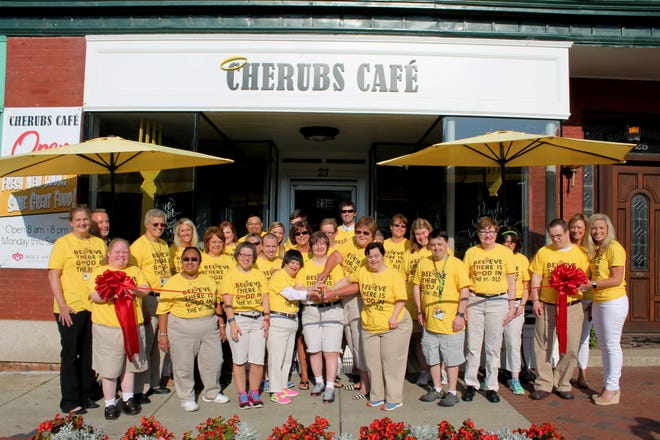 Wearing new "Believe There Is Good In The World" shirts, the Cherubs Cafe crew joined by staff members from Cherubs Candy Bouquets, Cherubs Cotton Candy Factory and Holy Angels celebrated the re-opening of the downtown Belmont restaurant with a Montcross Area Chamber ribbon-cutting on Aug. 22. Cherubs was closed for several weeks for a major renovation. The café and adjoining cotton candy factory and candy bouquet businesses are vocational programs of Holy Angels, providing job opportunities and community interaction for residents. Helping Holy Angels CEO Regina Moody cut the ribbon are Cherubs Cafe crew members (from left) Cheryl, Maria, Amy, Chris, Martha, Katie, Lorraine, Mac, Ellen, Tara and Taylor. Cherubs Café, at 23 N. Main St. in Belmont, offers a wide range of catering services and is open for breakfast and lunch and with a limited menu until 8 most evenings. For more information, call 704.825.0414, or visit www.holyangelsnc.org/cherubs. [Montcross Area Chamber photo/SPECIAL TO THE GAZETTE]