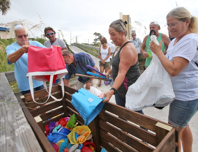 Volunteers add beach toys to a new “Take-a-toy, leave-a-toy” bin Tuesday at the M.B. Miller County Pier in Panama City Beach. The toy bin was set up to encourage beachgoers to leave unwanted toys in the wooden bin instead of leaving them in the sand. [PATTI BLAKE/THE NEWS HERALD]