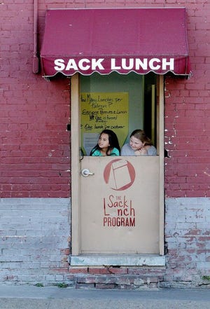 Destiny Galvan, left, and Madeline Partain wait to hand out free sack lunches Nov 19, 2016, at the St. John's Episcopal Church Sack Lunch Program doorway on N. B and Sixth streets. Through volunteers, St. John's gives away thousands of sack lunches every year to anyone who comes to their door. Destiny is the 10-year-old daughter of Jacqi Billingsly and Ray Galvan and Madeline is the 10-year-old daughter of Miel and Kevin Partain. JAMIE MITCHELL/TIMES RECORD