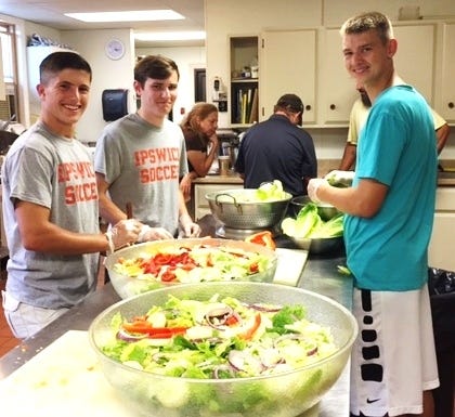 Members of the Ipswich High boys soccer team prepare salad for the Ipswich Dinner Bell meal on Aug. 21. From left to right are Captain Tyler Whynott, Captain Sean Davis and Chase Gagnon. [Courtesy Photo]