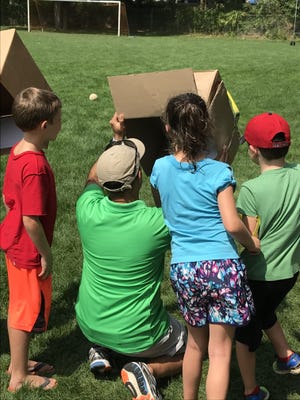 Dedham Community House Summer Camp parent and astronomer Ronak Shah teaches campers how to use a box pinhole projector to safely experience the solar eclipse. [Courtesy Photo]