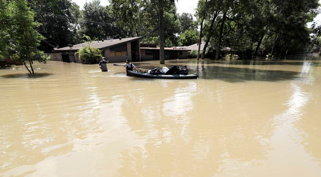 Gaston Kirby, right, and Juan Minutella leave Kirby’s flooded home in the aftermath of Hurricane Harvey, Monday, Sept. 4, 2017, near the Addicks and Barker Reservoirs, in Houston. (AP Photo/David J. Phillip)