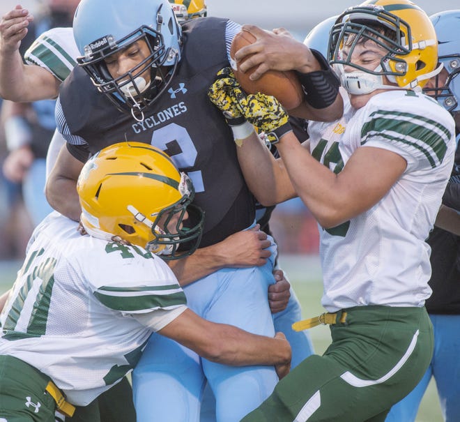Pueblo County High School’s Jaedon Vargas, right, takes a forearm to the face as he and teammate, Vincent Molinaro (40) do their best to bring down Pueblo West High School running back Pierre Taylor during first quarter action Friday September 1, 2017 at Cyclone Stadium in Pueblo West.