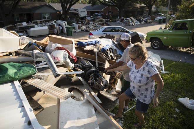 In this Wednesday, Sept. 6, 2017, photo, Blatt helps his neighbor Tamlyn Lima collect golf clubs from debris piled in front of her home in the aftermath of Hurricane Harvey in Houston. Harvey's record-setting rains now have the potential to set records for the amount of debris one storm can produce. (AP Photo/Matt Rourke)