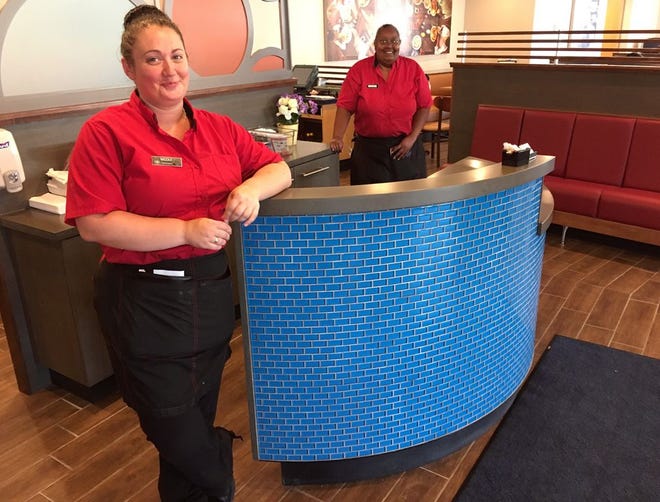 IHOP assistant manager Nicole Rolls, front, and server Dawn Souto, rear, stand near a new hostess station in the newly redesigned Raynham restaurant, which closed in June after a fire.