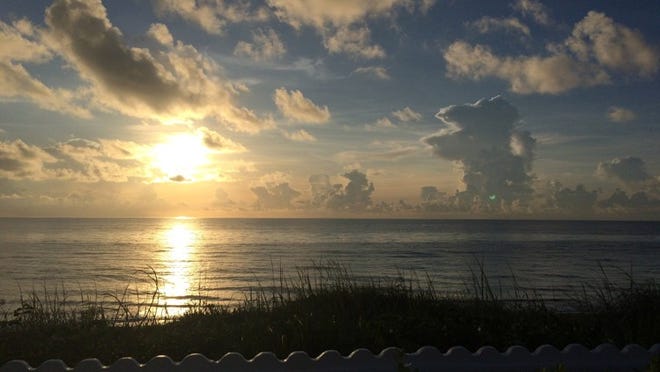 At Midtown Beach in Palm Beach, the sun rises over a calm Atlantic Ocean Thursday. Darrell Hofheinz / Daily News