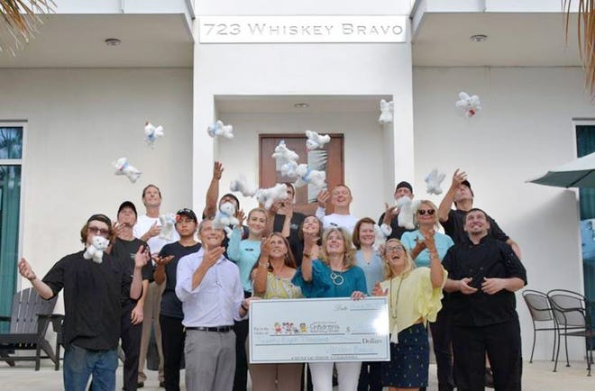 The staff at 723 Whiskey Bravo restaurant in Seagrove Beach, headed up by General Manager Michael Schoettle, celebrates raising $28,000 to benefit the Pierce Family Children’s Advocacy Center through guest donations for Riley therapy dog stuffed animals this past year. [SPECIAL TO THE SUN]