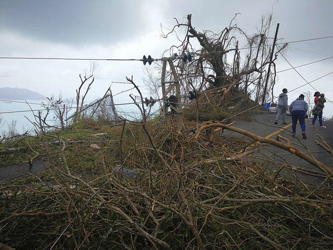 In this Thursday, Sept. 8, 2017 photo, a resident ducks under a downed power line in the aftermath of Hurricane Irma in Tortola, in the British Virgin Islands. (Jalon Manson Shortte via AP)