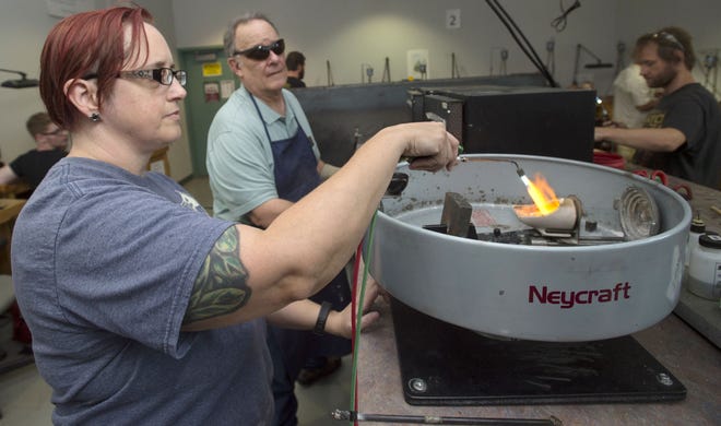 CHIEFTAIN PHOTO/BRYAN KELSEN Pueblo Community College jewelry instructor David Edwards looks on as Kim Kowalski utilizes a torch during a jewelry-making class Wednesday. Kowalski utilizes what some would consider bizarre materials in her craft, including animal bones.