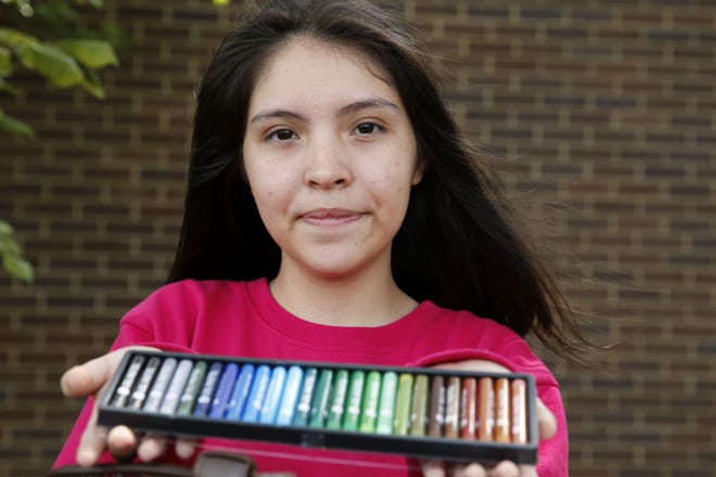 Annette Quintana, 14, of La Porte, Texas, shows off some of her art supplies Aug. 30 outside the Walnut Hill Recreation Center, a shelter for hurricane Harvey evacuees in Dallas. [DALLAS MORNING NEWS]