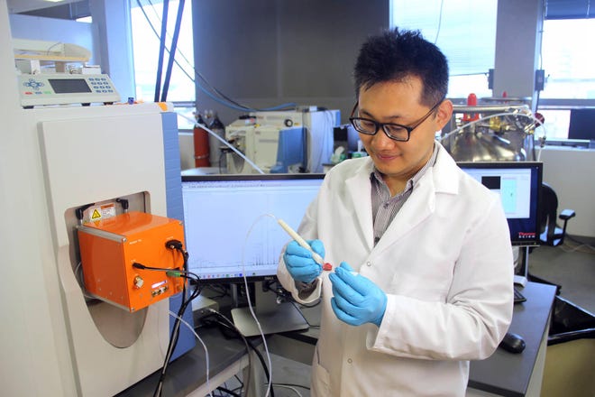 This photo provided by the University of Texas at Austin, shows scientist Jialing Zhang as he demonstrates using the MasSpec Pen to analyze a human tissue sample. Scientists are developing a highly experimental pen-like probe to help surgeons better tell when it’s safe to stop cutting or if stray tumor cells still lurk. (University of Texas at Austin via AP)