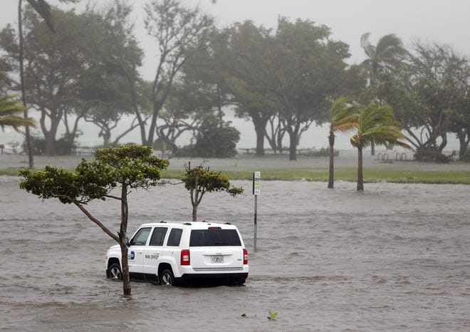 A park officer's vehicle sits in a flooded parking lot at Haulover Park as Hurricane Irma passes through the area Sunday in North Miami Beach. As Hurricane Irma leaves Florida, the focus will shift to recovery. And that will cost money — more than what local communities can afford. Although skies may clear, the financial forecast for many governments looks gloomy. [WILFREDO LEE / ASSOCIATED PRESS]