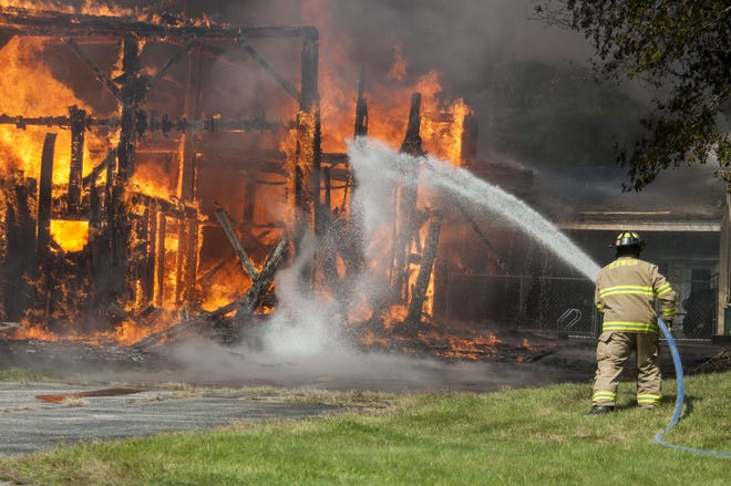 Firefighter Bob Couture tackles a three-alarm fire on Sunday that destroyed a barn on Hubbard Road in Berwick, Maine. [Erin Thomas/Fosters.com]