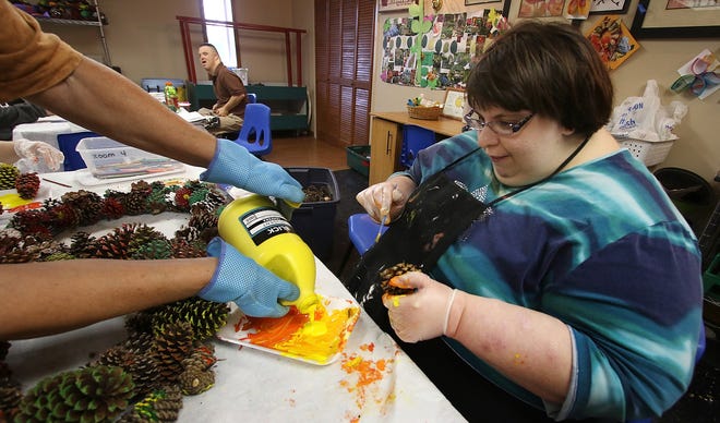 Judith Jaeger pours yellow paint into a dish for Molly who decorates pine cones to be sold at an upcoming fundraiser at ComServ on Delta Drive on Tuesday morning, Aug. 29, 2017. [Mike Hensdill/The Gaston Gazette]