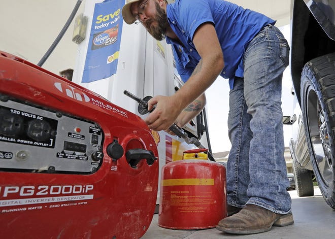 In this Aug. 24 AP file photo, Aaron Berg fills up a gas can and his portable generator in Houston as Hurricane Harvey intensifies in the Gulf of Mexico.
