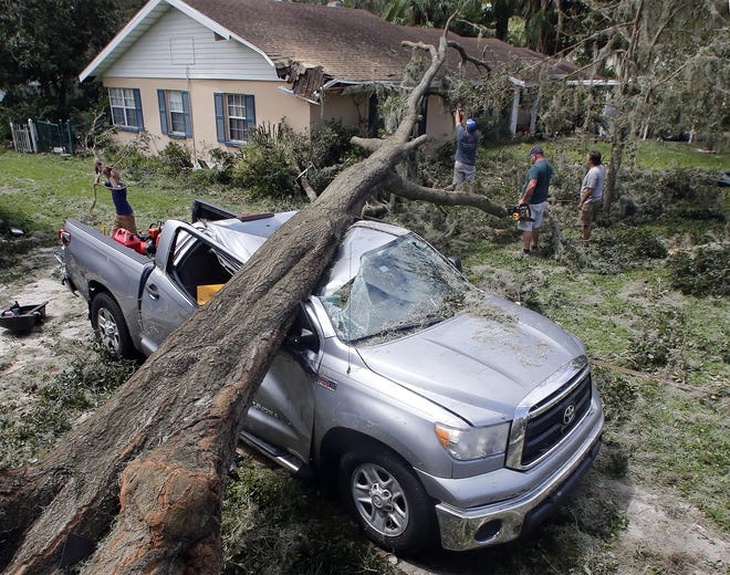 Jon Eckman works on cutting up the tree that crushed his truck during Hurricane Irma in Bartow.   [ PIERRE DUCHARME/THE LEDGER ]