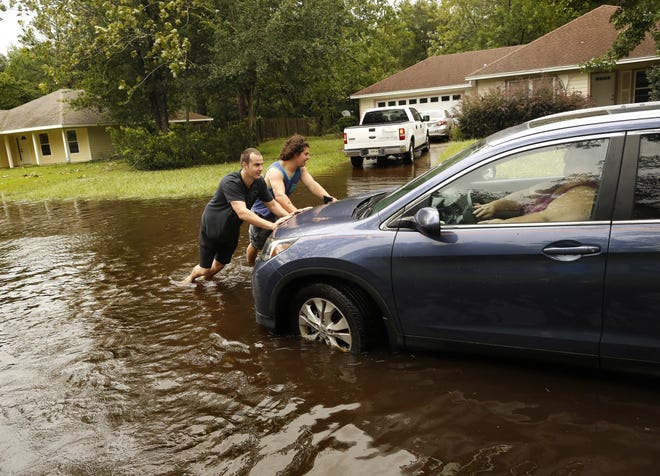 Brandon Trionfo, right, and Alex Broz help push a neighbor's car out of a flooded street in the Northwood Pines neighborhood of Gainesville, after Hurricane Irma hit the area, on Monday. [Brad McClenny/Staff photographer]