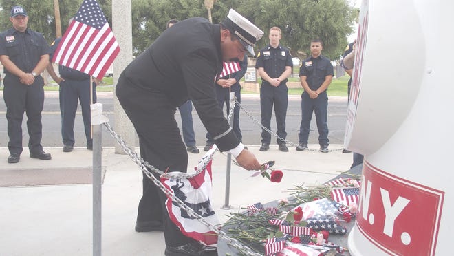 Capt. Nick DiNapoli of the Barstow Fire Department places a flower at the memorial fire helmet that honors the 343 fire personnel who were lost on Sept. 11, 2001. [Kay Lovato, Daily Press]