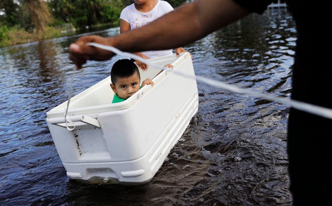 Alfonso Jose Jr., 2, is floated down his flooded street by his parents as the wade through water to reach an open convenience store in the wake of Hurricane Irma in Bonita Springs, Fla., Tuesday, Sept. 12, 2017. (AP Photo/David Goldman)