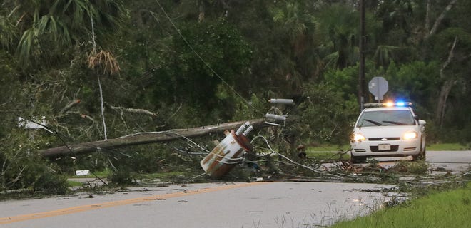 A sheriff's deputy checks out a fallen power pole as the aftermath of Hurricane Irma becomes clear Monday morning, Sept. 11, 2017. [News-Journal/Jim Tiller]