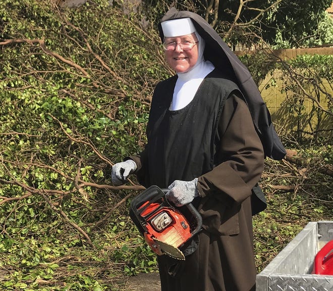 In this Tuesday, Sept. 12, 2017, photo provided by the Miami-Dade Police Department, Sister Margaret Ann holds a chain saw near Miami, Fla. Police said the nun was cutting trees to clear the roadways around Archbishop Coleman Carrol High School in the aftermath of Hurricane Irma. (Miami-Dade Police Department via AP)
