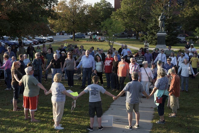 A chorus of "We Shall Overcome" rises from a gathering against racism in Broad Street Park in Claremont, N.H., Tuesday, Sept. 12, 2017. The demonstration was inspired by violence last month against an 8-year-old biracial boy that occurred while he played with a group of teenagers outside his home. [James M. Patterson/The Valley News via AP]