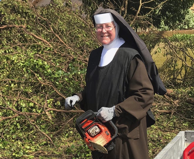 In this Sept. 12 photo provided by the Miami-Dade Police Department, Sister Margaret Ann holds a chain saw near Miami. Police said the nun was cutting trees to clear the roadways around Archbishop Coleman Carrol High School in the aftermath of Hurricane Irma. [AP PHOTO]