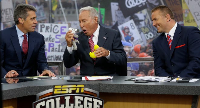 FILE - In this Oct. 12, 2013, file photo, ESPN College GameDay host Lee Corso, center, talks to mascots from the Washington Huskies and the Oregon Ducks as he makes his prediction of an Oregon win over Washington in an NCAA college football game during College GameDay's broadcast from Red Square on the University of Washington campus in Seattle. At left is co-host Chris Fowler, and at right is co-host Kirk Herbstreit. ESPN’s “College GameDay” will broadcast from Times Square on Sept. 23, the first time the popular pregame road show travels to New York City. (AP Photo/Ted S. Warren, File)