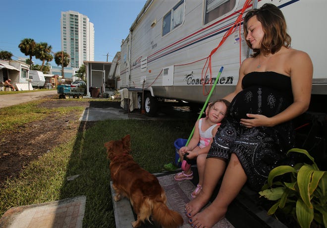 Holly Hill resident Amy Sweet taking a break from storm cleanup with Payeton Therrien, her neighbor's 3-year-old granddaughter, on the steps of her travel trailer at Riverside Community manufactured home park on Riverside Drive. “I gotta hold my baby up,” said Sweet, who is nine months pregnant and several days overdue. “I feel like he’s gonna fall outta there.” [News-Journal/Nigel Cook]
