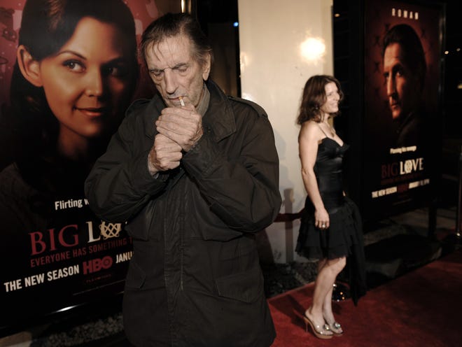 FILE - In this Jan. 14, 2009, file photo, actor Harry Dean Stanton, left, a cast member in the HBO series "Big Love," lights a cigarette as fellow cast member Melora Walters poses on the red carpet at the show's third season premiere in Los Angeles. Legendary character actor Stanton has died at age 91. Stanton's agent John S. Kelly says the actor died of natural causes Friday afternoon, Sept. 15, 2017, at Cedars-Sinai Medical Center in Los Angeles. (AP Photo/Chris Pizzello, File)