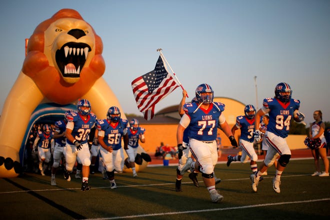 The Moore High School football team takes the field to play Norman during the Lions' homecoming football game on Thursday. [PHOTO BY BRYAN TERRY, THE OKLAHOMAN]