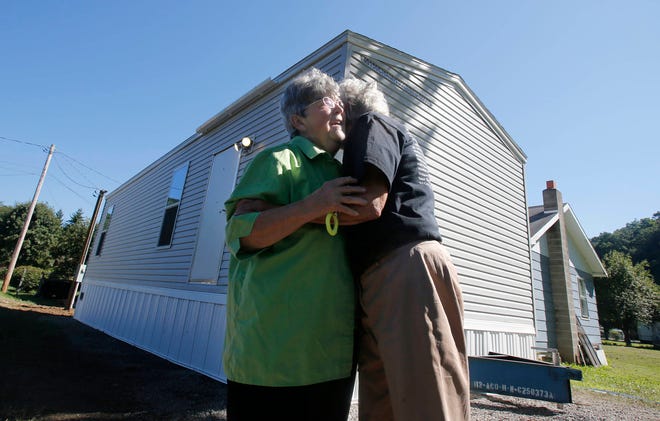 FILE - In this Aug. 23, 2016, file photo, Mayor Andrea “Andy” Pendleton, right, hugs resident Linda Bennett in front of Bennett’s new FEMA trailer installed in front of her flood ravaged home in Rainelle, W. Va. Just before Hurricane Harvey made landfall in Texas in August 2017 as a Category 4 hurricane and in the floods that ensued, the federal government was auctioning off used disaster-response trailers at fire-sale prices. (AP Photo/Steve Helber, File)
