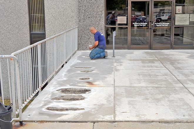 A workman from Northern Industrial grinds out low spots at the Branch County Courthouse entrance and fills them with epoxy. Don Reid photo