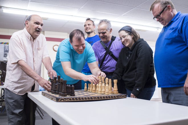 Participants in the U.S. Blind Chess Championship in Lindsborg examine the carved wooden pieces of an elaborate chess set during a break in the tournament. They are Albert Pietrolungo, from left, Alexander Barrasso, Timur Gareyev (in back), James Thoune, Jessica Lauser and Mark Wood.. [PHOTO COURTESY JIM TURNER]