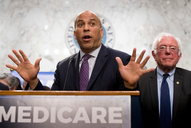 Sen. Cory Booker, D-N.J., left, accompanied by Sen. Bernie Sanders, I-Vt., right, speaks during a news conference on Capitol Hill in Washington, Wednesday, Sept. 13, 2017, to unveil their Medicare for All legislation to reform health care.