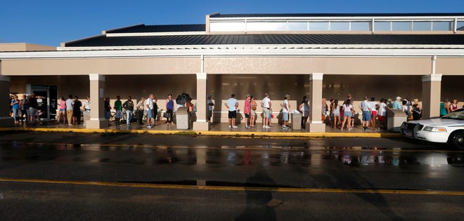 People line up for the announced opening of a Publix grocery store, the first food chain to re-open in Naples, in the aftermath of Hurricane Irma, which passed through Sunday, in Naples, Fla., Tuesday, Sept. 12, 2017. The store could not open its doors on time because they were trying to get the cash registers online. (AP Photo/Gerald Herbert)