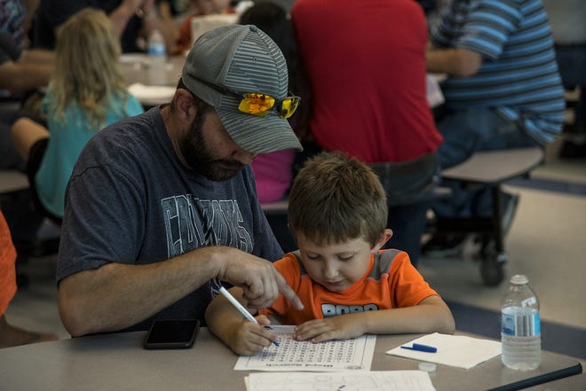 David McKelvey, left, and his son Wyatt McKelvey, who is in kindergarten at Silas Willard, work on a word search activity during the Watch DOGS presentation Tuesday. [MITCH PRENTICE/The Register-Mail]