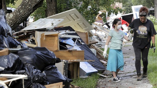 Jenny Killingsworth, right, holds the hand of Janeah Tieman, 10, while cleaning up a home damaged by Hurricane Harvey floodwaters on Sept. 4 in Houston. (AP Photo/David J. Phillip)